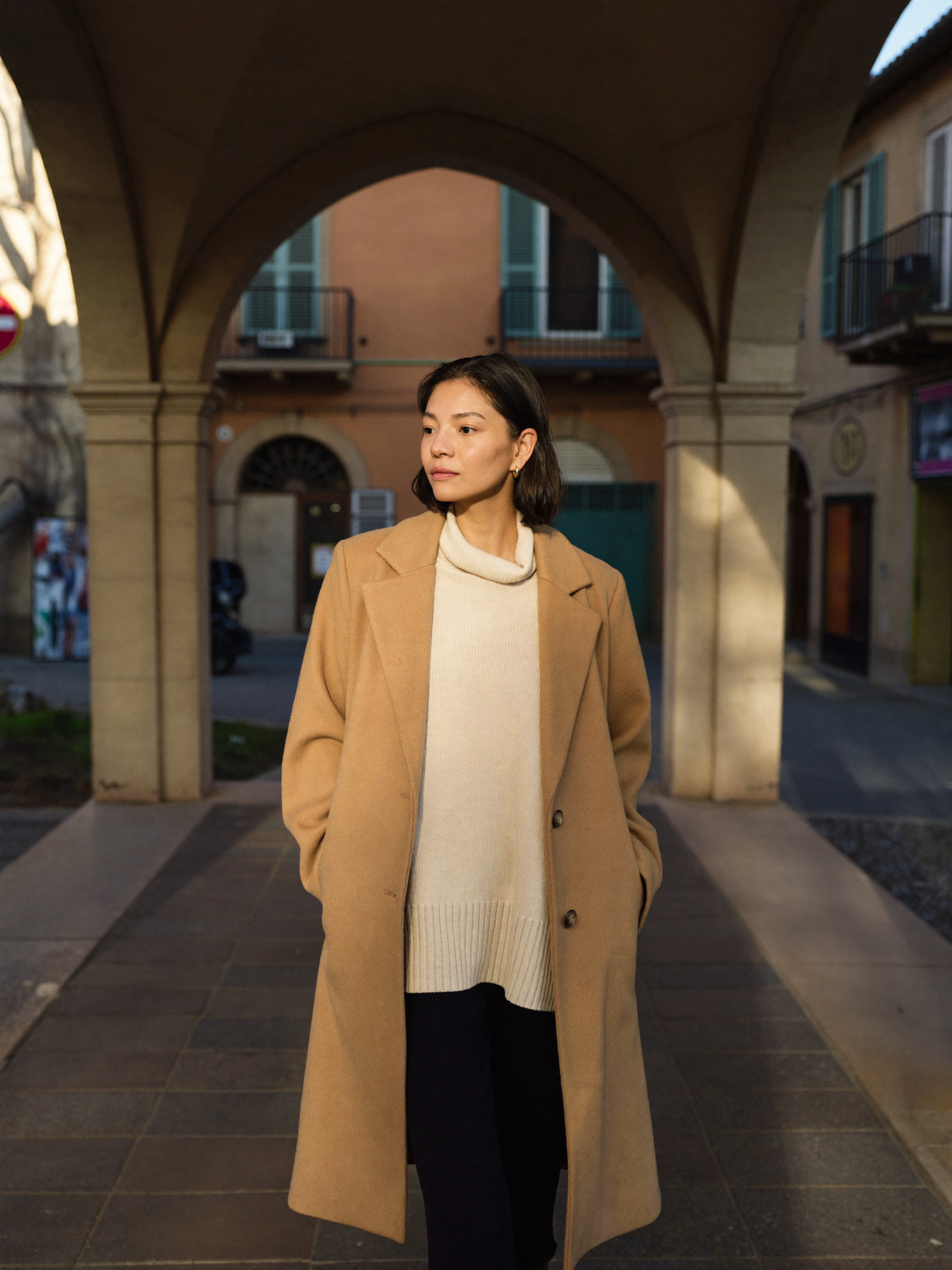 Donna con cappotto cammello sotto un portico italiano